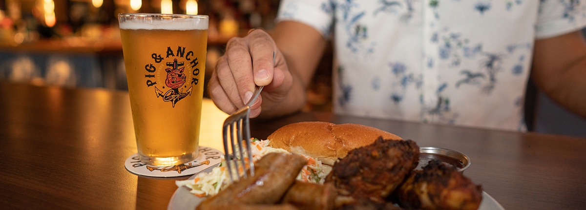 a guest eats a meal and drinks a beer at guys pig and anchor smokehouse brewhouse